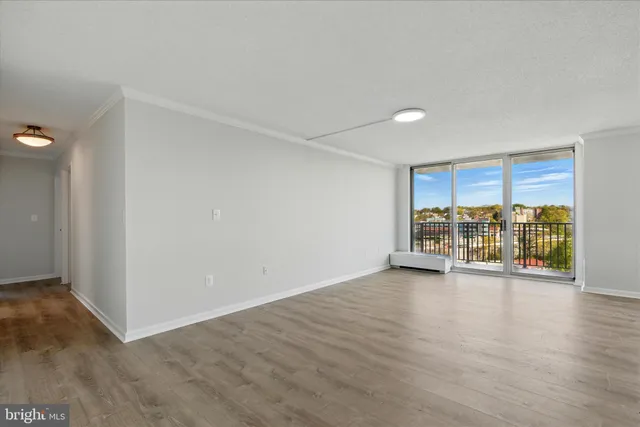 a view of an empty room with a window and wooden floor