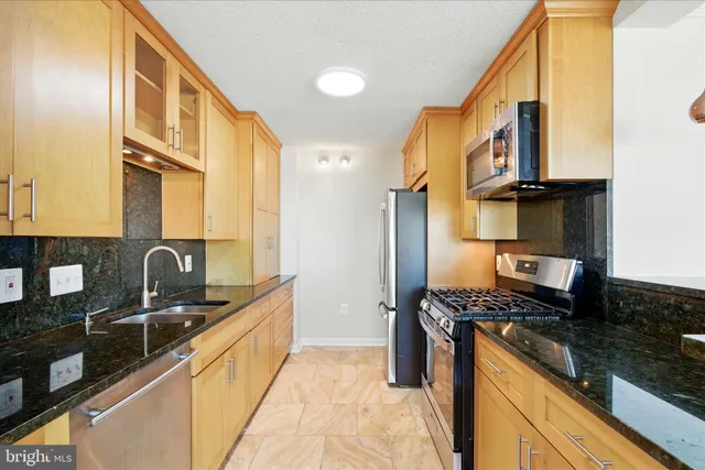 a kitchen with granite countertop a sink a counter top space cabinets stainless steel appliances and a counter top space