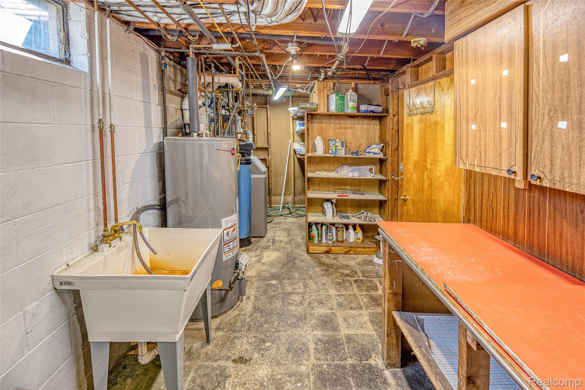 2855 Farmers Creek Road Metamora, MI 48455 - Photo 35 of 51 Utility room featuring a laundry sink, exposed copper plumbing, a water heater, a water softener, and wood-finish shelving