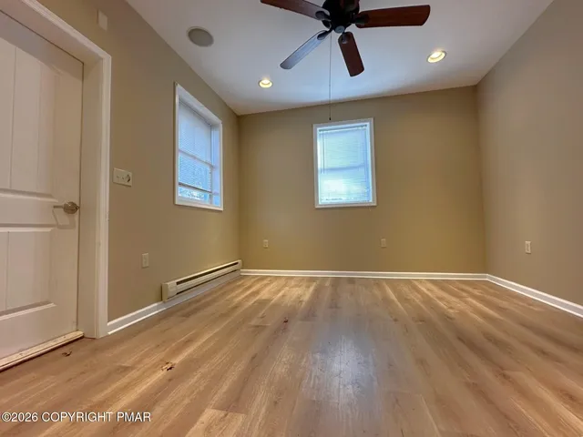 a view of an empty room with wooden floor and a window