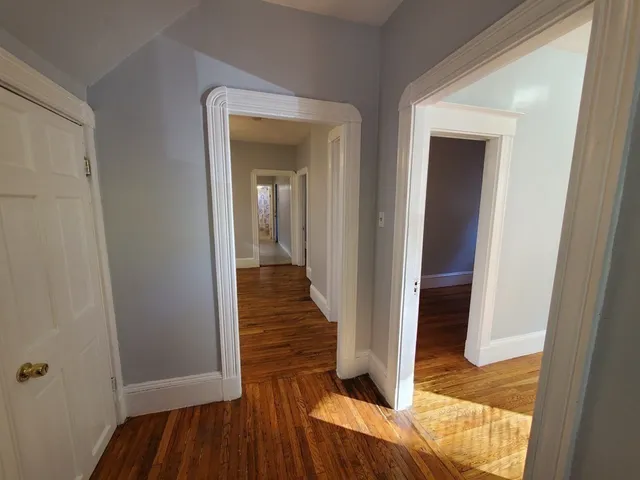 a view of a hallway with wooden floor and closet