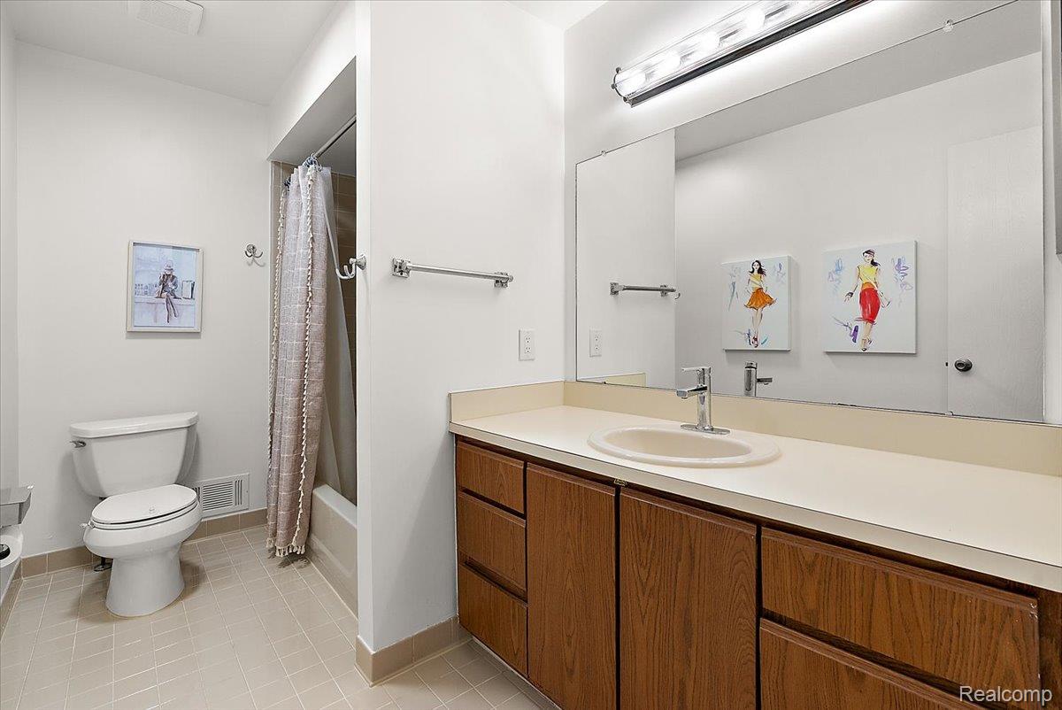 552 Tennyson Rochester, MI 48307 - Photo 22 of 36 Bathroom featuring a wood-finish vanity with a built-in sink, a large wall-mounted mirror, and a combined shower and tub