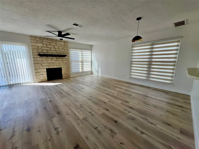 a view of empty room with wooden floor and ceiling fan