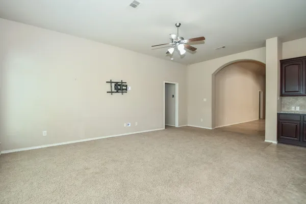 an empty room with chandelier fan and windows