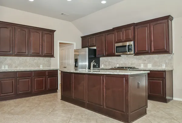 a kitchen with granite countertop wooden cabinets a stove a oven and a granite counter top