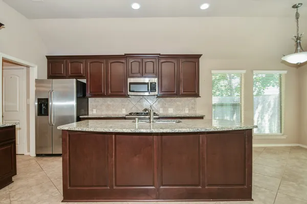 a kitchen with stainless steel appliances granite countertop a sink and a refrigerator