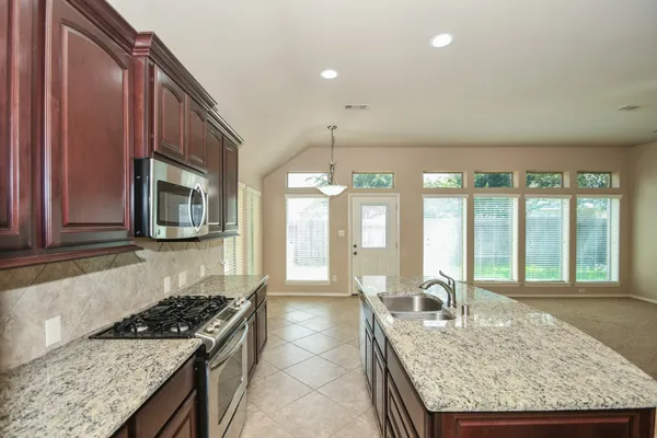 a kitchen with granite countertop sink stove and refrigerator