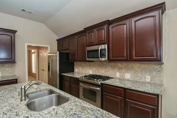 a kitchen with granite countertop stainless steel appliances and wooden cabinets