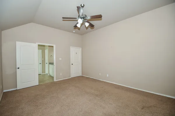 an empty room with a chandelier fan and windows