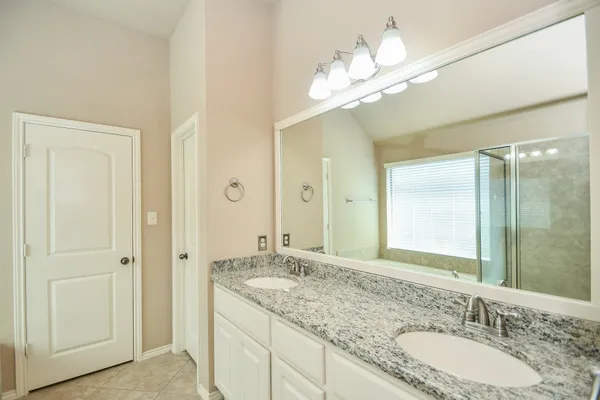 a bathroom with a granite countertop sink a large mirror and a shower