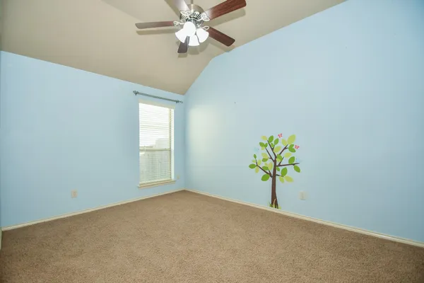 an empty room with chandelier fan and windows