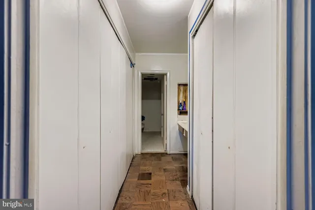 a view of a hallway with wooden floor and a bathroom