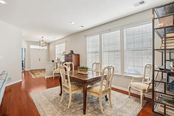 a kitchen with stainless steel appliances granite countertop wooden cabinets a sink a stove a dining table and chairs