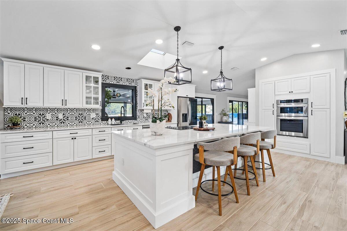 470 Rio Vista Lane Merritt Island, FL 32952 - Photo 11 of 54 a kitchen with stainless steel appliances kitchen island granite countertop a wooden floor and white cabinets