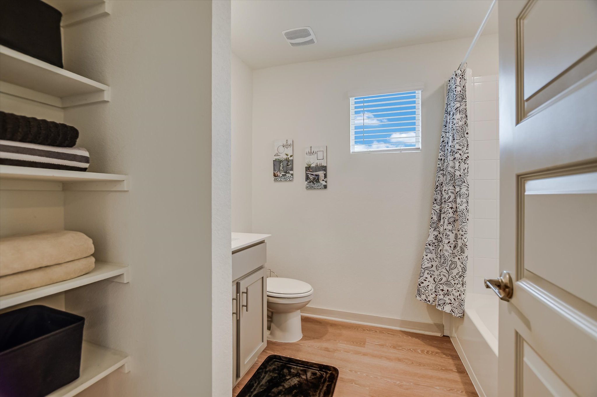 105 Merrick Road Georgetown, TX 78628 - Photo 14 of 23 A compact, functional bathroom features practical open shelving and a tub-shower combination with a bright window.