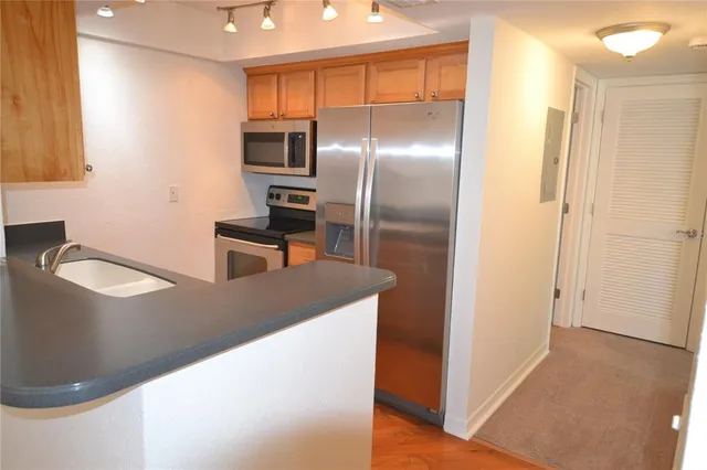 a kitchen with stainless steel appliances granite countertop a refrigerator a stove and a sink