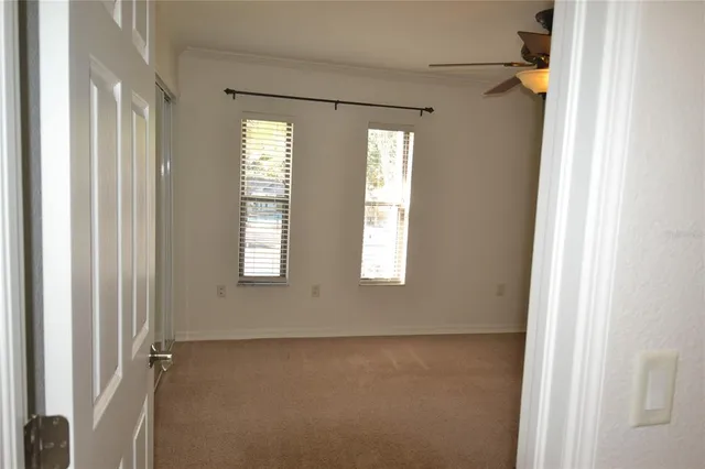 an empty room with window and chandelier fan