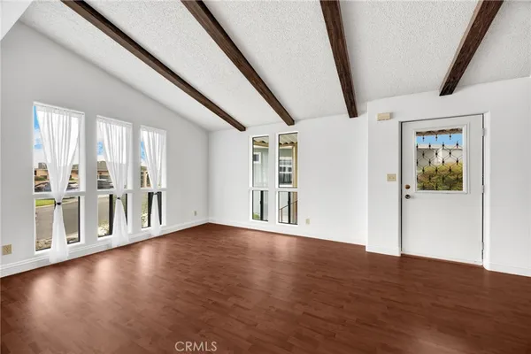 a view of an empty room with wooden floor and windows