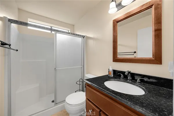 a bathroom with a granite countertop sink toilet a mirror and shower