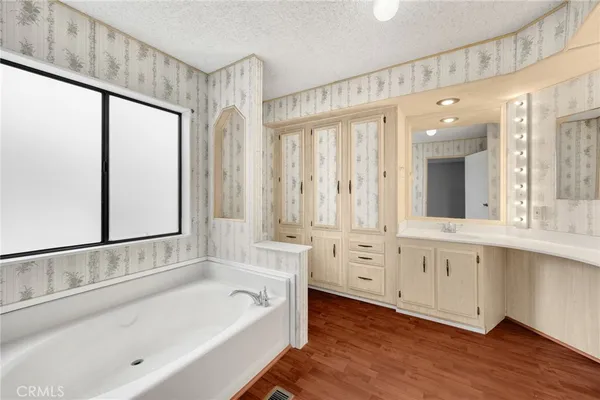 a bathroom with a bathtub a double vanity sink and mirror