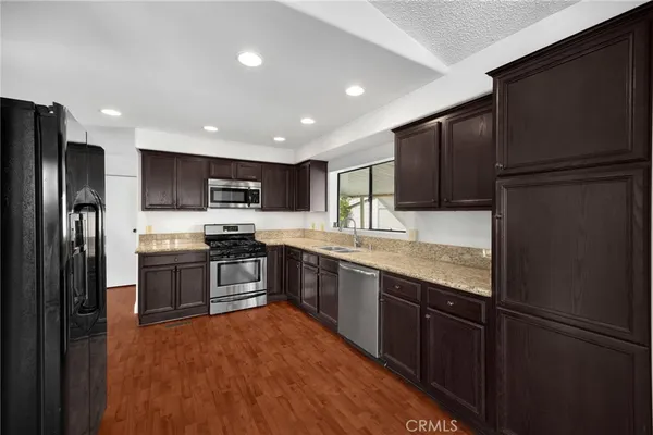 a large kitchen with stainless steel appliances granite countertop a refrigerator and a stove top oven