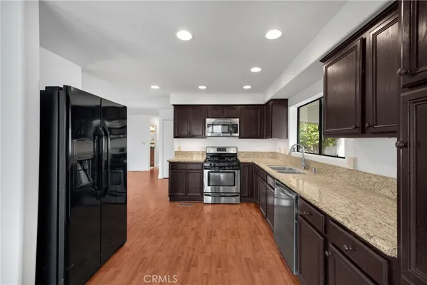 a large kitchen with granite countertop a large counter top stainless steel appliances and cabinets