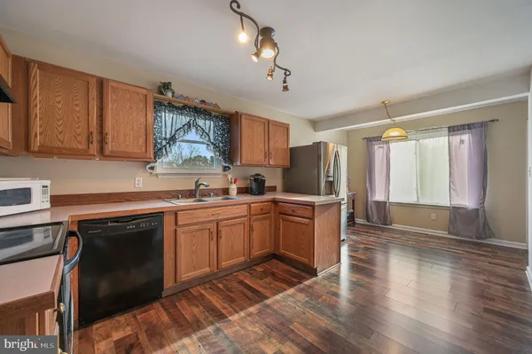 a kitchen with granite countertop a stove top oven a sink dishwasher and a refrigerator with wooden floor