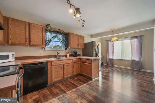 a kitchen with granite countertop a stove top oven a sink dishwasher and a refrigerator with wooden floor