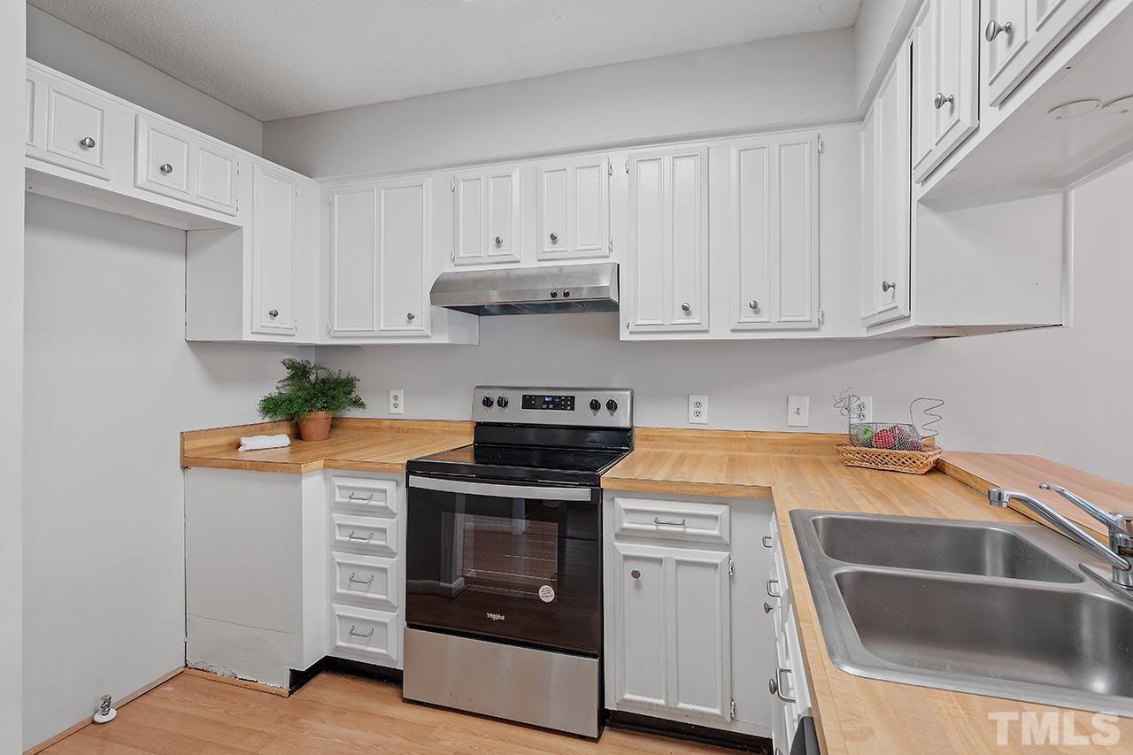700 Green Ridge Drive Raleigh, NC 27609 - Photo 4 of 33 a kitchen with stainless steel appliances granite countertop a stove and white cabinets