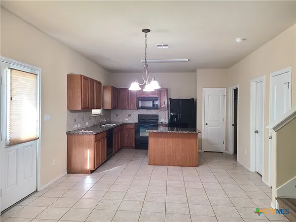 a large kitchen with granite countertop a stove a sink dishwasher a refrigerator and a oven with white cabinets