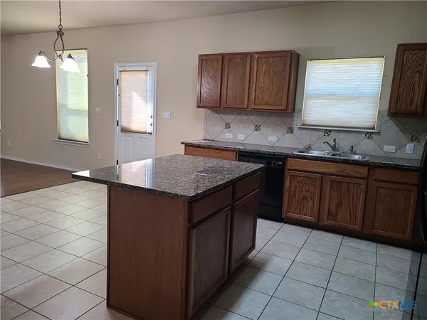 a kitchen with a sink a stove cabinets and wooden floor