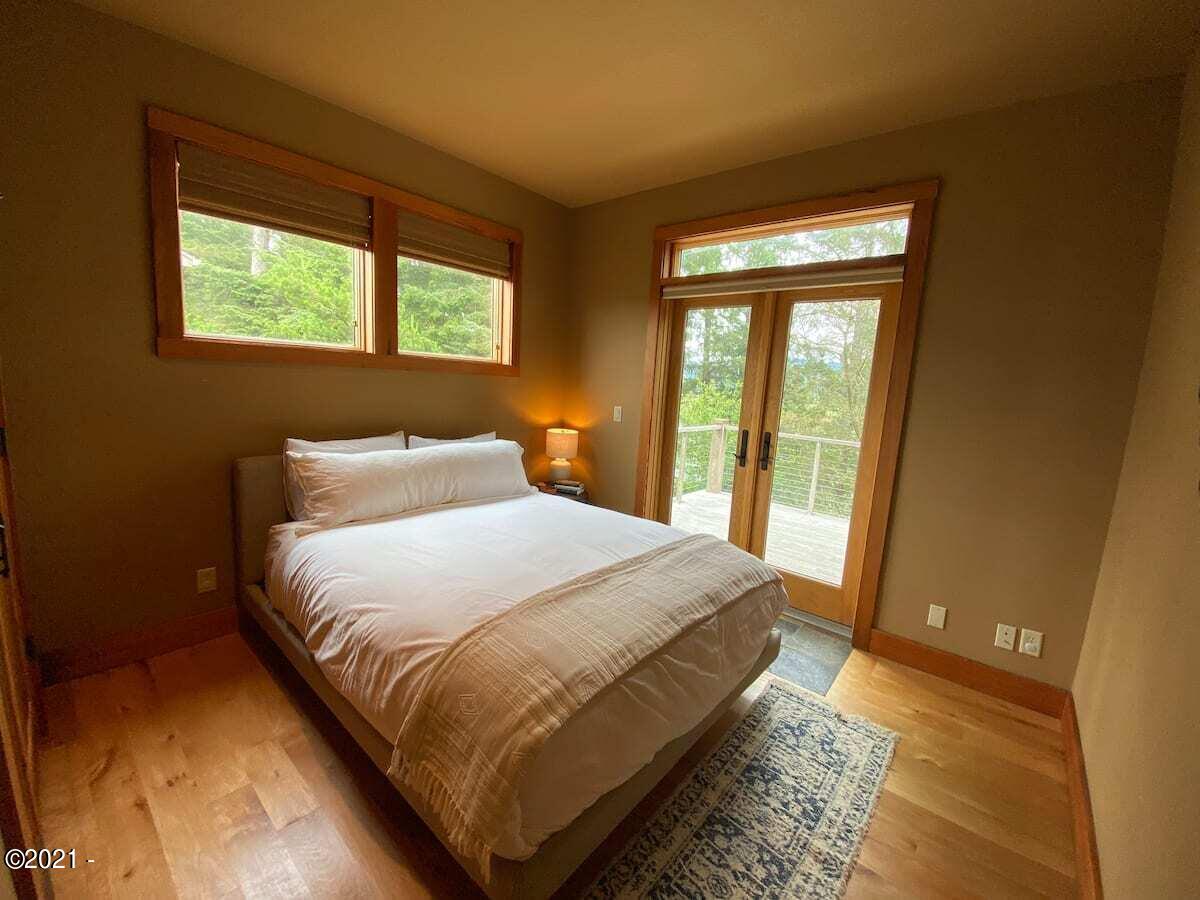 6355 Nestucca Ridge Road Pacific City, OR 97135 - Photo 11 of 20 a bedroom with a bed lamp and a large window