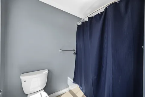 a bathroom with a toilet and a shower curtain