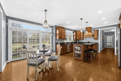 a dining room with stainless steel appliances granite countertop furniture wooden floor and a kitchen view