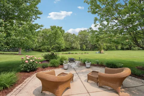 a view of a swimming pool and lounge chairs in back yard of the house