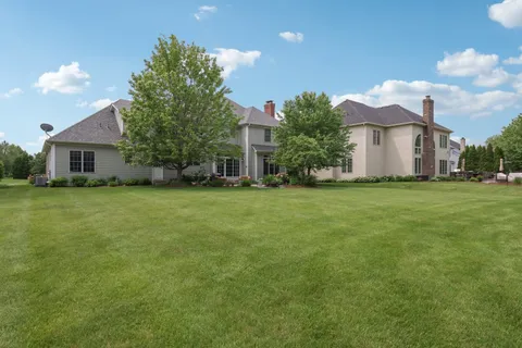 a view of a house with a big yard and large trees