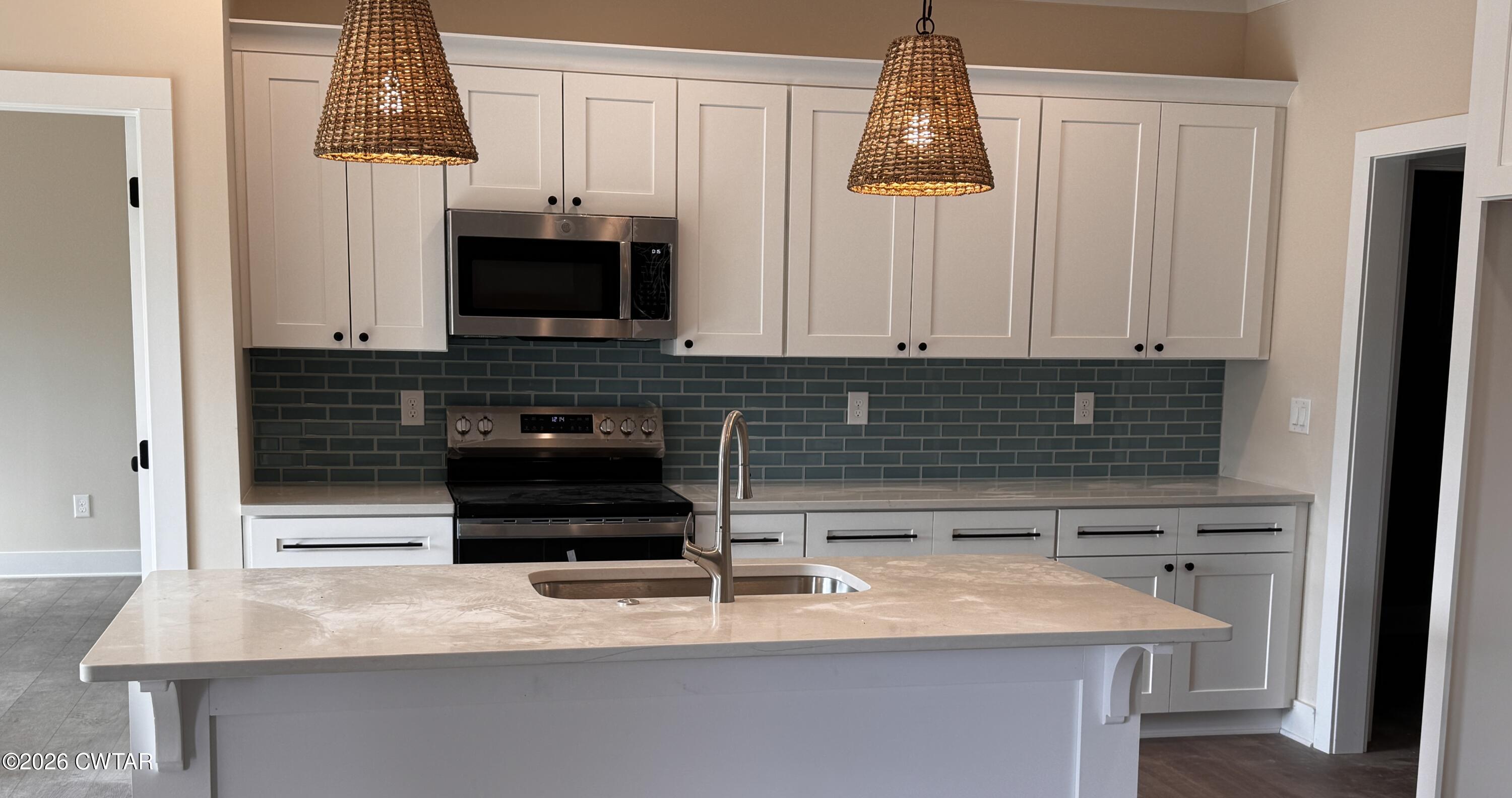 24 Tea Berry Cove Jackson, TN 38305 - Photo 8 of 16 a kitchen with granite countertop a stove a sink and a microwave