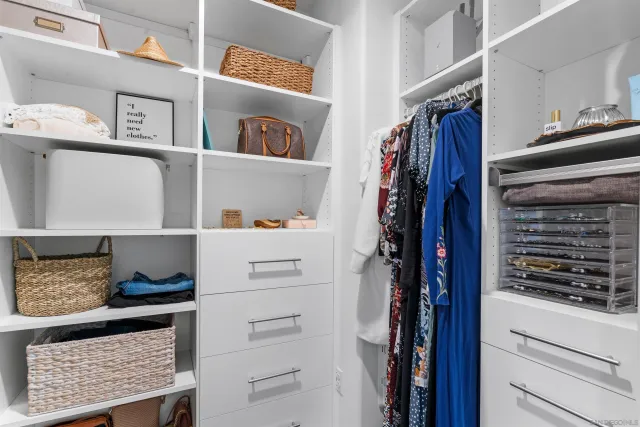 a view of walk in closet with clothes and shoes