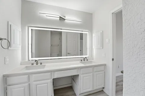 a bathroom with a double vanity sink a mirror and a bathtub