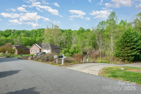 a view of a house with a big yard plants and large trees