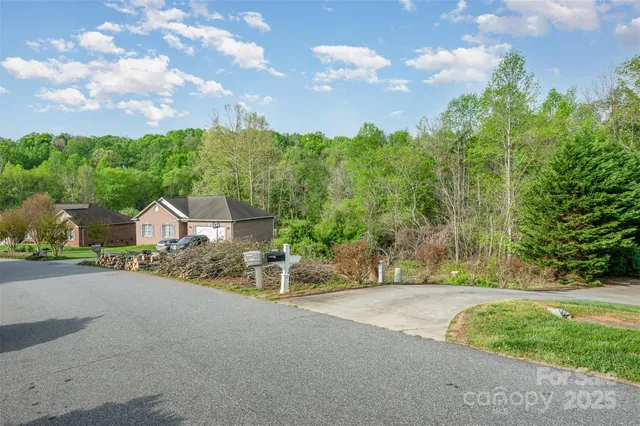 a view of a house with a big yard plants and large trees