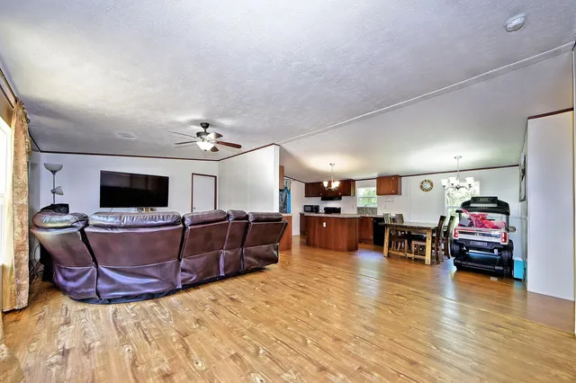 a kitchen with stainless steel appliances granite countertop a stove a refrigerator a sink a dining table and chairs with wooden floor