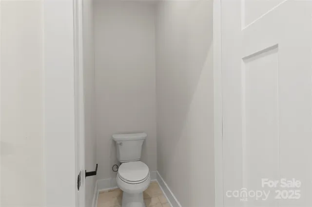 a white toilet sitting next to a white wall