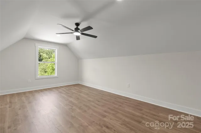 an empty room with wooden floor ceiling fan and windows