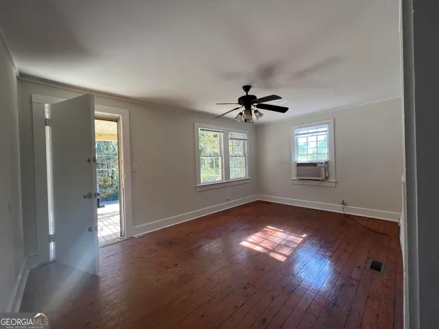 a view of empty room with wooden floor and fan