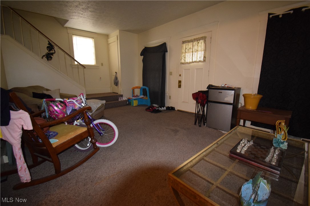 913 Lawrence Road Northeast Canton, OH 44704 - Photo 5 of 10 Carpeted living room featuring a textured ceiling and stairway