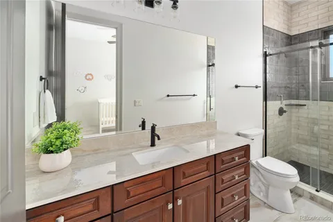 a bathroom with a granite countertop sink a toilet and shower