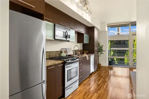 a kitchen with stainless steel appliances granite countertop a refrigerator a stove top oven a sink and dishwasher