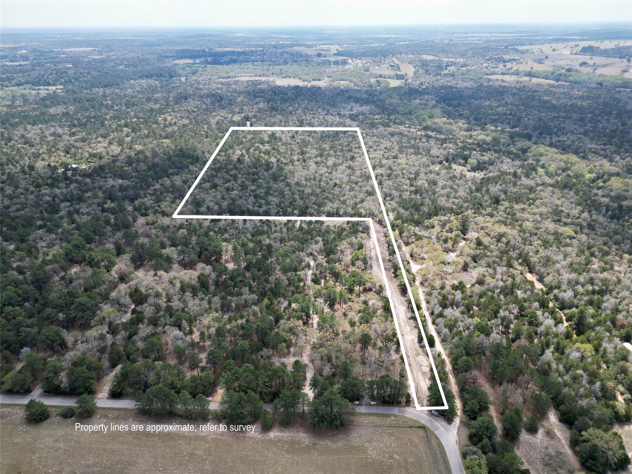 797 Marlin Street McDade, TX 78650 - Photo 1 of 10 Aerial view of property and surrounding area featuring property boundaries highlighted and a heavily wooded area