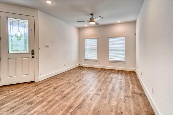 a view of an empty room with wooden floor and window